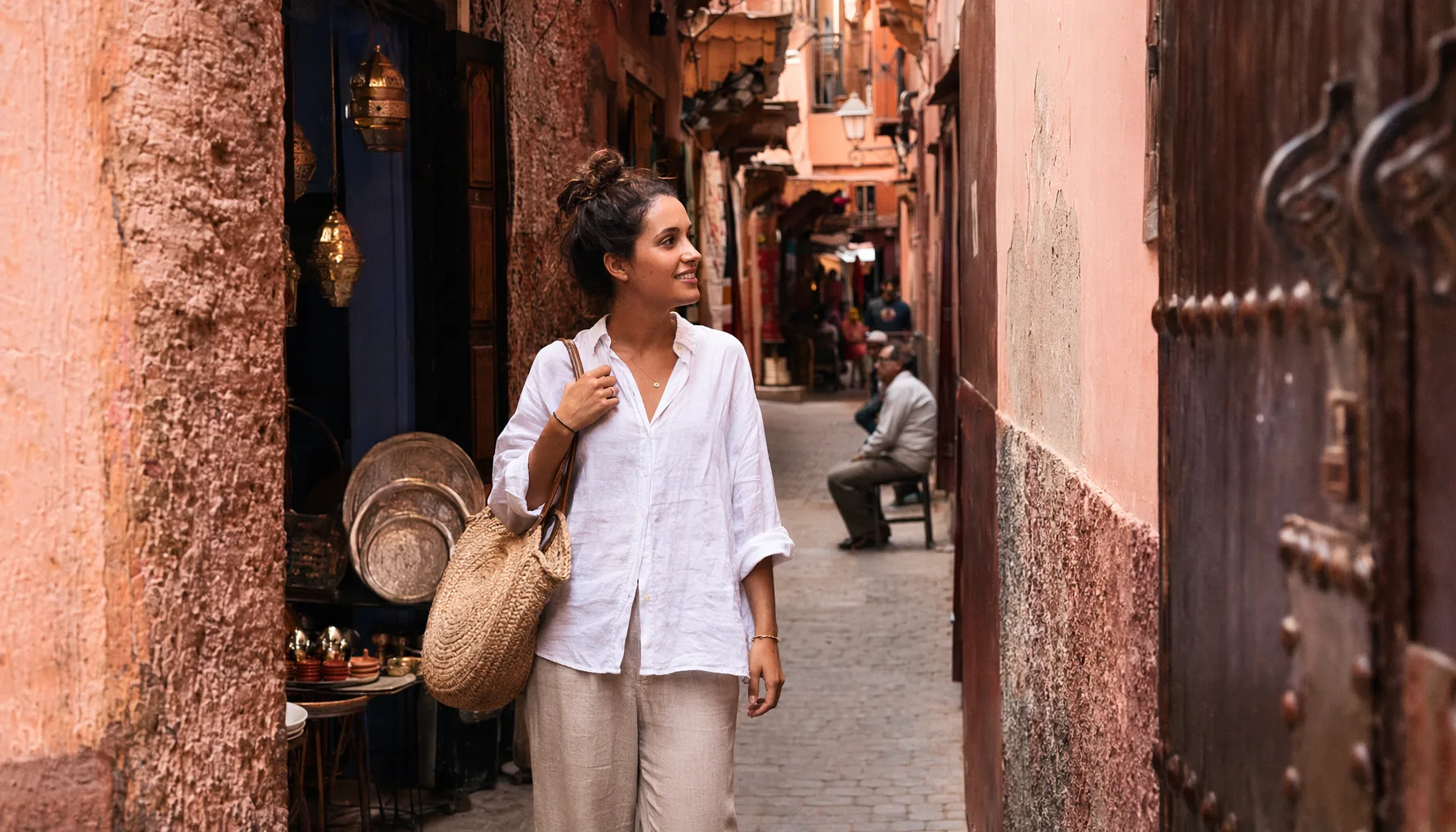 Femme voyageant seule à Marrakech, terrasse de café ou ruelle de la médina en journée, attitude détendue et confiante