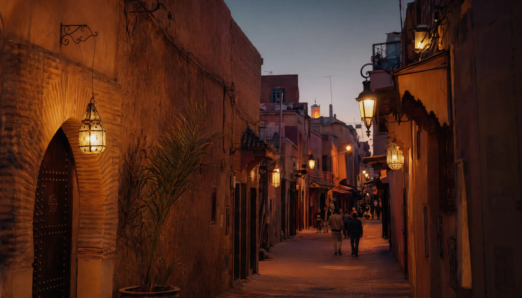 Ruelle de la médina de Marrakech à la tombée de la nuit, lanternes allumées, passants visibles