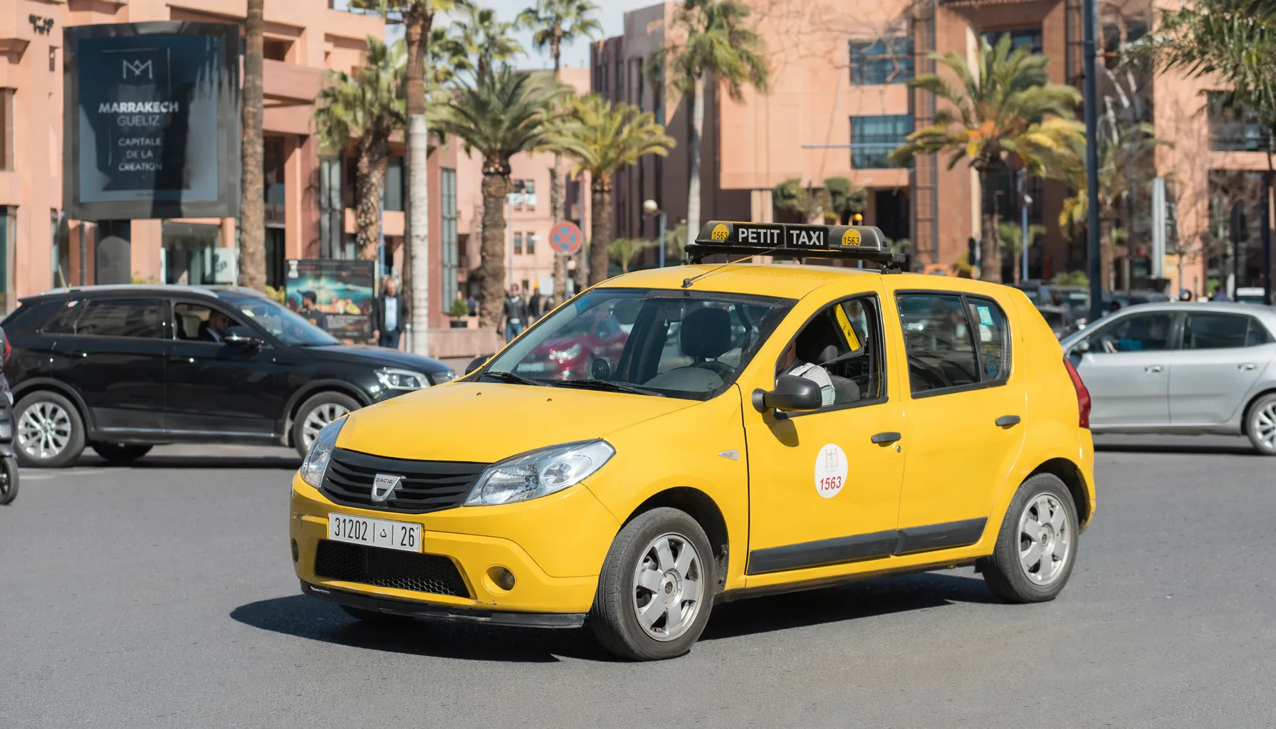 Petit taxi jaune dans une rue de Marrakech, circulation urbaine, quartier moderne