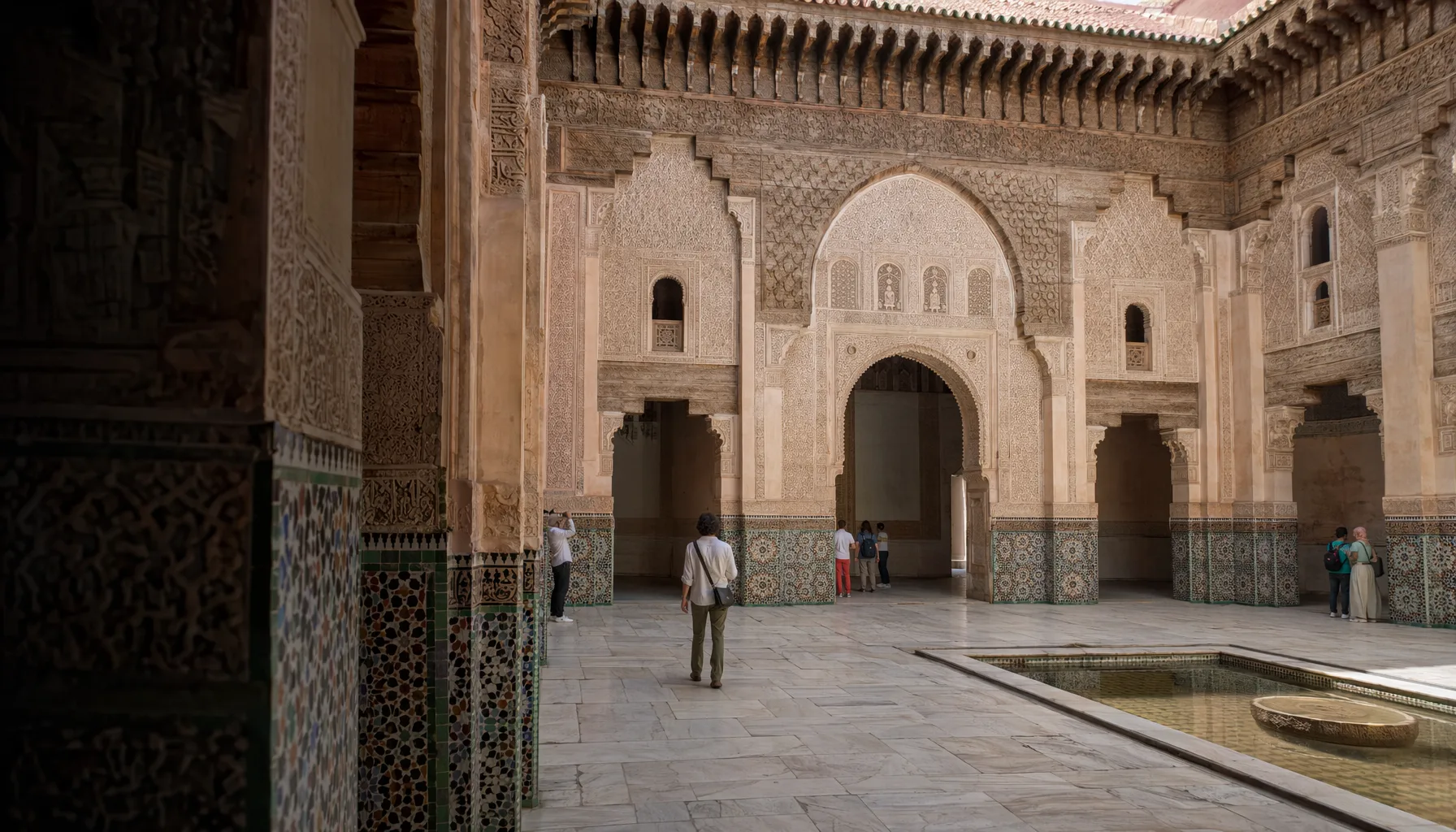 Cour intérieure de la medersa Ben Youssef à Marrakech, lumière naturelle, visiteurs visibles
