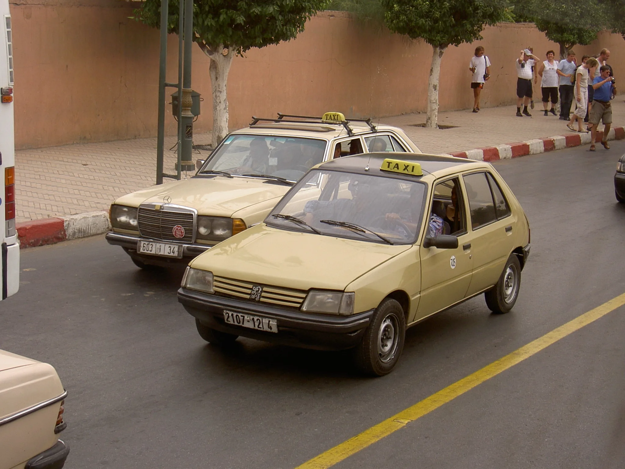 Small beige taxis on a Marrakech street, a Peugeot and a Mercedes