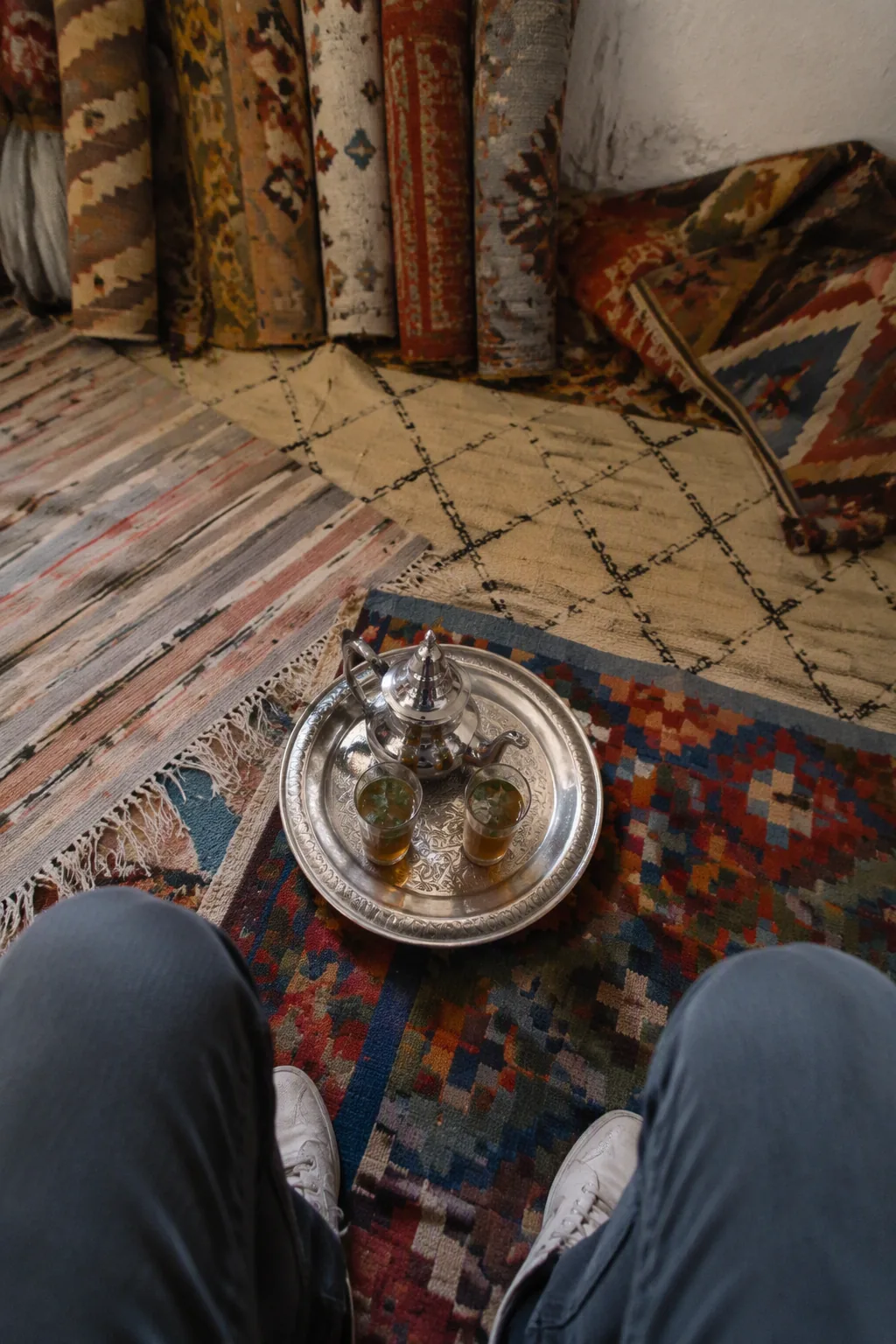 Tray of mint tea set on unrolled rugs in a shop in the medina